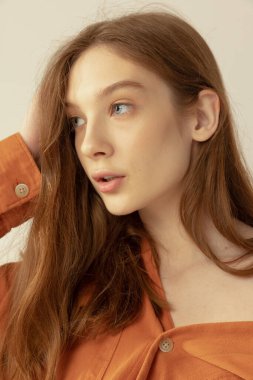 Gri stüdyo arka planında izole edilmiş güzel kızıl saçlı kızın yakın plan portresi. Çıplak makyaj bakışı. Doğal güzellik kavramı, sağlık, vücut ve cilt bakımı, spa, kozmetoloji, fitness, reklam