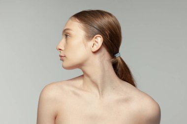 Gri stüdyo arka planında izole edilmiş at kuyruklu genç bir kızın portresi. Kozmetik bilimi tedavi görüyor. Güzellik kavramı, doğal ten, kozmetoloji, spa, plastik süphe, tıp