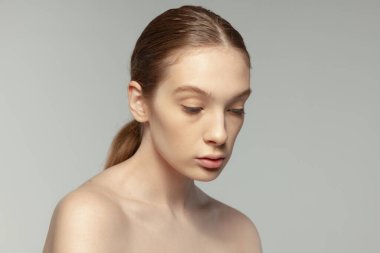 Net bir yüzü olmayan genç bir kızın portresi gri stüdyo arka planında izole edilmiş. Sağlıklılık. Kadın cilt bakımı. Güzellik kavramı, doğal ten, kozmetoloji, spa, plastik süphe, tıp