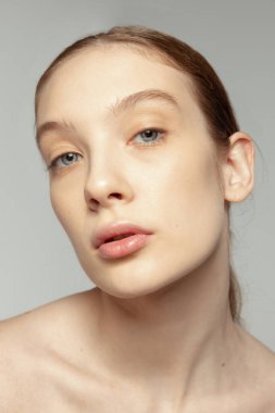 Gri stüdyo arka planında izole edilmiş pürüzsüz tenli güzel bir kızın yakın plan portresi. Cilt kozmetolojisi. Güzellik kavramı, doğal cilt, kozmetik, spa, plastik sugery, tıp