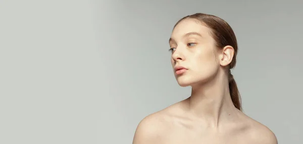 ポニーテールが低く メイク顔もグレーのスタジオ背景に孤立していない公開少女 化粧品の顔のケア ナチュラルスキン プラスチックサギー 医学の概念 — ストック写真