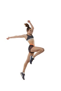 Uzun atlama sporunda hareketlerin gelişimi. Beyaz arka planda izole bir şekilde atlayan, spor üniformalı profesyonel bir bayan sporcu. Spor, eylem, hareket, hız kavramı. İlan için alanı kopyala