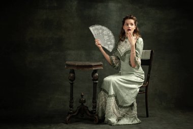 - Sürpriz. Şok. Ortaçağ moda tarzında gri elbiseli güzel bir kızın klasik portresi koyu arka planda izole edilmiş. Flaman tarzı, dönemin konseptiyle kıyaslama. Klasik sanat karakteri, yaşlı