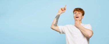 Bir fikrim var. Stüdyo resmi, beyaz tişörtlü genç bir adam, mavi stüdyo arka planında izole edilmiş poz veriyor. Gençlik kavramı, moda, duygular, yüz ifadesi. İlan için alanı kopyala