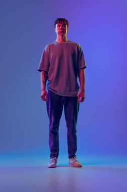 Surat asma. Genç, kızıl saçlı bir adam, mavi stüdyonun arka planında izole edilmiş bir öğrenci. Gençlik kavramı, moda, duygular, yüz ifadesi. İlan için alanı kopyala