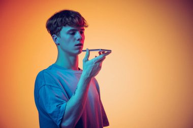 Genç kızıl saçlı bir adam sarı arka planda izole edilmiş bir telefon kullanıyor. Gençlik kavramı, moda, duygular, yüz ifadesi. İlan için alanı kopyala