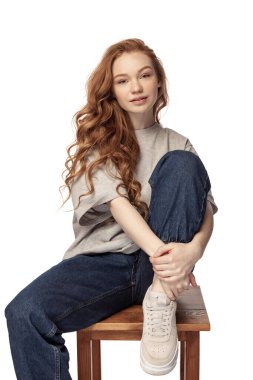 Gülümseyen model. Beyaz arka planda izole edilmiş kameraya bakan uzun kıvırcık saçlı güzel bir kızın portresi. Sıradan giyinmiş bir kız öğrenci. Gençlik, güzellik, hayat kavramı. İlan için alanı kopyala