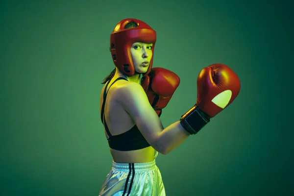 冲啊霓虹灯绿色背景下隔离的运动防护装备中专业女性拳击手的肖像 业余爱好 成功的概念 — 图库照片