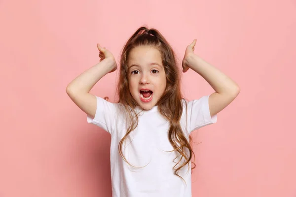 기쁨이야 스튜디오에서는 귀여운 소녀가 분홍색 배경에 고립된 티셔츠를 아이를 촬영했습니다 — 스톡 사진