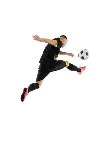 蹴って 白い背景に隔離されたプロの男性サッカー選手のトレーニングのダイナミックな肖像画 スポーツ 広告の概念 黒のサッカーキットを身に着けている — ストック写真