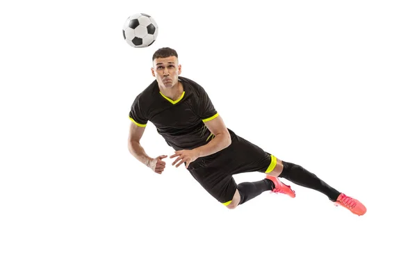 頭を蹴って 白いスタジオの背景に隔離されたプロの男性サッカー選手のトレーニングの肖像画 スポーツ 広告の概念 黒のサッカーキットを身に着けている — ストック写真