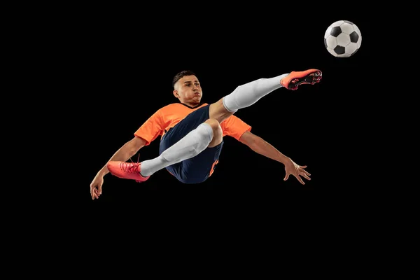 フライト 暗い背景に隔離された動きのプロの男性サッカー選手の肖像画 スポーツ 広告の概念 オレンジブルーのサッカーキットを着たスポーツマン — ストック写真