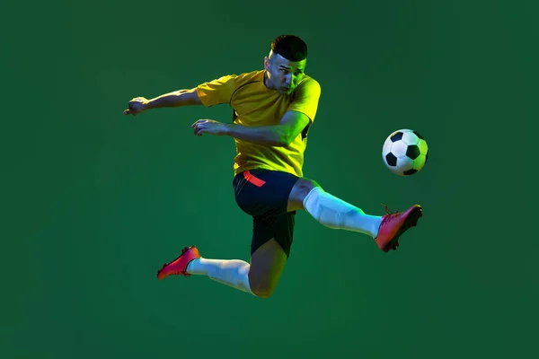 运动中的职业男性足球运动员的动态肖像 在黑暗的背景下被隔离 体育的概念 身穿橙色 蓝色足球套件的运动员 — 图库照片