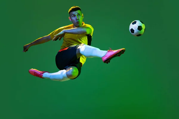 职业男足运动员在黑暗背景下的运动肖像 体育的概念 身穿橙色 蓝色足球套件的运动员 — 图库照片