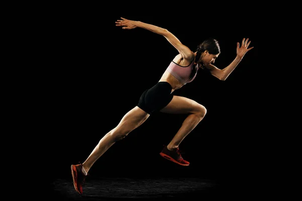 演播室拍摄年轻的肌肉发达的女人在黑色背景下孤独地奔跑 田径运动 竞赛和积极的生活方式概念 文字的复制空间 — 图库照片