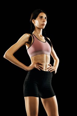 Başlamadan önce konsantrasyon. Siyah arka planda izole edilmiş, spor üniformalı genç bayan sporcunun portresi. Spor, atletizm, yarışma konsepti. İlan, metin için boşluk kopyala