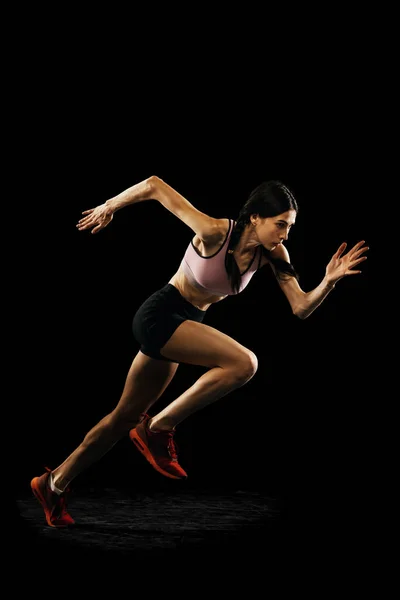 行动中 演播室拍摄年轻的肌肉发达的女人在黑色背景下孤独地奔跑 田径运动 竞赛和积极的生活方式概念 文字的复制空间 — 图库照片