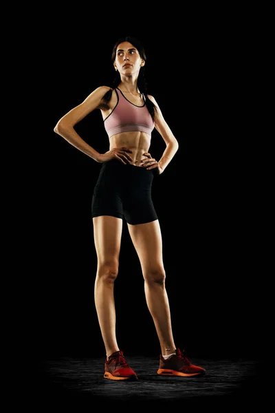 若い女の子の完全な長さの肖像画 黒のスタジオの背景に隔離されたポーズスポーツの制服を着た女性選手 スポーツ 陸上競技 競技のコンセプト テキストのコピースペース — ストック写真
