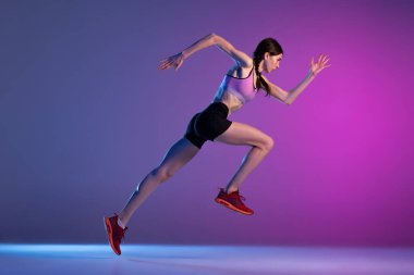 İş üstündeyken. Genç kaslı bir kız, bayan koşucu ya da koşucu eğitimi neon ışıkta pembe-mavi arka planda izole edilmiş. Spor, atletizm, rekabet ve aktif yaşam tarzı konsepti.
