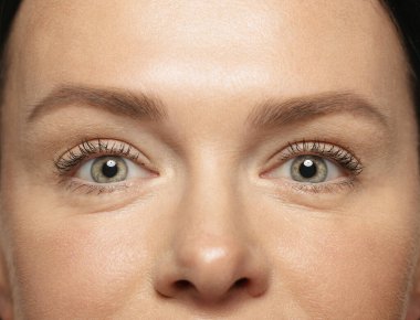 Genç kadın gözlerinin ilk kırışıklıklarla yakın plan portresi. İyi korunmuş ciltli bir kadın model. Kadınların sağlık ve güzellik kavramı, kozmetik, kozmetik, kendine bakım, cilt bakımı. Yaşlanma Karşıtı.