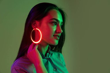 Küpeler. Moda neon aksesuarları olan genç ve güzel bir kız. Hafif arka planda izole edilmiş mücevherler. Güzellik kavramı, dijital moda tarzı, yaratıcılık, dijitalleştirme, teknoloji çağı, bilişim