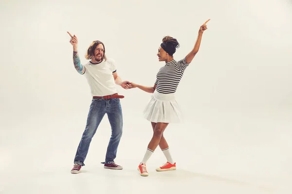 Hippie. Stylish man and woman in vintage retro style outfits dancing isolated on white background. Timeless traditions, 1960s american fashion style and art. Dancers look happy, delighted