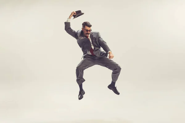 Shock, fear. Jumping man, businessman wearing grey striped suit in 50s, 60s fashion style isolated on white background. Concept of modern culture, beauty, ad and fashion. Copy space for ad.