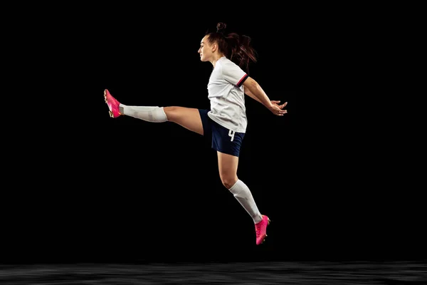 一个精力充沛的高加索女人 运动中的足球运动员在黑暗的背景下被隔离 游戏和健身概念 穿着足球套件的年轻运动员 — 图库照片
