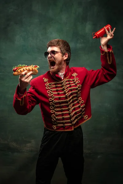 Mladý Muž Obleku Jako Královský Husar Ochutnávající Velký Hot Dog — Stock fotografie