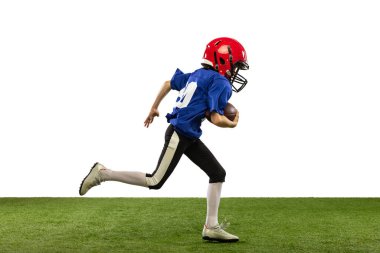 Küçük çocuğun dinamik portresi, Amerikan futbol eğitiminin acemi oyuncusu yeşil çimen döşemeli beyaz arka planda izole edilmiş. Spor anlayışı, hareket, başarılar. İlan için alanı kopyala