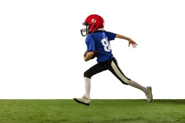 Spor üniformalı ve ekipmanlı Amerikan futbolu oynayan küçük bir çocuk neon ışıkta yeşil arka planda izole edilmiş. Spor, reklam, hareket, başarı kavramı.