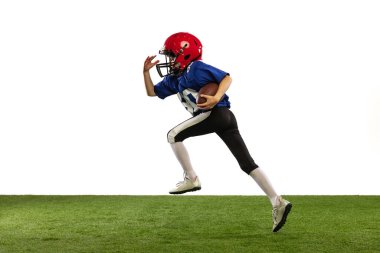 Küçük çocuğun dinamik portresi, Amerikan futbol eğitiminin acemi oyuncusu yeşil çimen döşemeli beyaz arka planda izole edilmiş. Spor anlayışı, hareket, başarılar. İlan için alanı kopyala