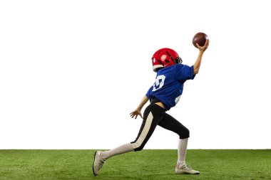 Küçük çocuğun dinamik portresi, Amerikan futbol eğitiminin acemi oyuncusu yeşil çimen döşemeli beyaz arka planda izole edilmiş. Spor anlayışı, hareket, başarılar. İlan için alanı kopyala