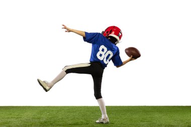 Hareket halinde. Atletik çocuk, beyaz arka planda izole edilmiş spor üniformalı Amerikan futbolcusu ve kask eğitimi. Spor kavramı, zorluklar, eylem, başarılar.