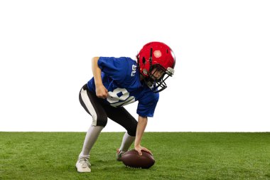 Hareket halinde. Atletik çocuk, beyaz arka planda izole edilmiş spor üniformalı Amerikan futbolcusu ve kask eğitimi. Spor kavramı, zorluklar, eylem, başarılar.