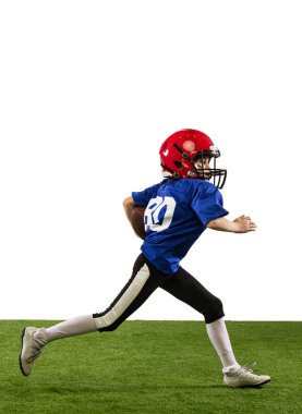 Küçük çocuğun dinamik portresi, Amerikan futbol eğitiminin acemi oyuncusu yeşil çimen döşemeli beyaz arka planda izole edilmiş. Spor anlayışı, hareket, başarılar. İlan için alanı kopyala