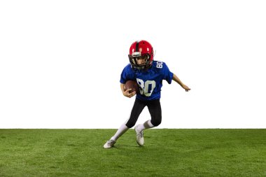 Hareket halinde. Atletik çocuk, beyaz arka planda izole edilmiş spor üniformalı Amerikan futbolcusu ve kask eğitimi. Spor kavramı, zorluklar, eylem, başarılar.