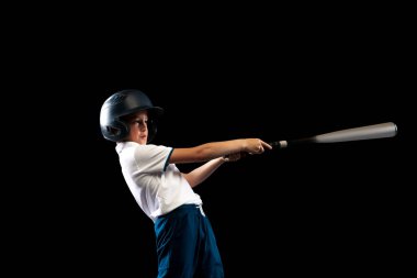 Vuruş. Sportif çocuk, siyah arka planda yarasa izole edilmiş spor üniformalı yeni beyzbol oyuncusu. Spor anlayışı, başarılar, rekabet. Okul çağındaki çocuk beyzbol oynamayı öğreniyor.