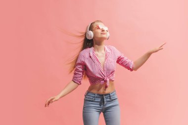 Dans ediyorum. Pembe arka planda uzun sarı saçlı, ekose gömlekli güzel bir kızın portresi. İnsan duyguları kavramı, yüz ifadesi, gençlik, arzu, reklam