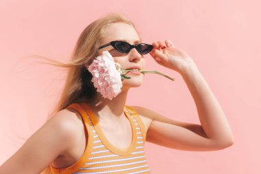 Güzellik. Pembe arka planda izole bir şekilde poz veren yaz moda koleksiyonu kıyafetli güzel bir kızın stüdyo fotoğrafı. Duyguların kavramı, yüz ifadesi, gençlik, arzu, satış