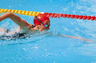 Yüzme havuzunda. Sportif bir kadın, yüzme şapkası takmış ve halka açık havuzda gözlük eğitimi almış. Tatil, aktif yaşam tarzı, güç, enerji, spor hareketi konsepti. Yaz zamanı.