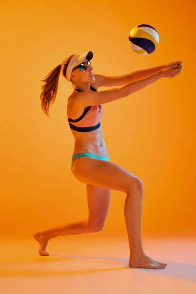 沙滩排球 活泼的年轻女子 排球运动员的训练与球隔离的橙色背景 健康的生活方式 健身理念 夏季运动会 — 图库照片