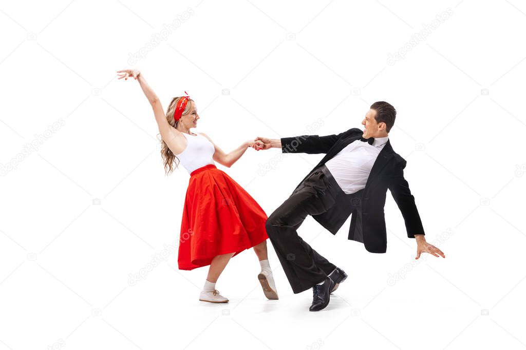 Expressive couple of dancers in vintage retro style outfits dancing social dance isolated on white background. Timeless traditions, 60s ,70s american fashion style. Dancers look excited