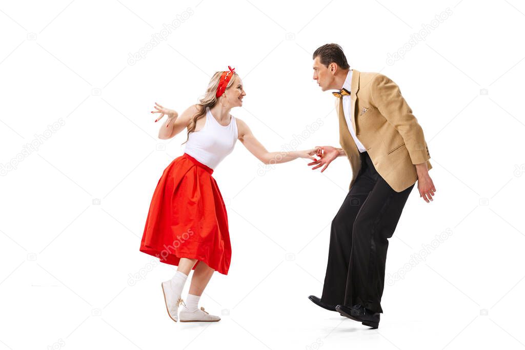 Live and emotions. Excited young couple of dancers in vintage retro style outfits dancing social dance isolated on white background. Timeless traditions, 60s ,70s american fashion style.