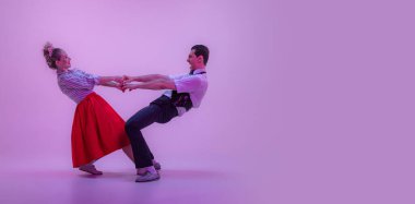 El ilanı. Kaliteli genç adam ve güzel kadın klasik kıyafetlerle dans ediyorlar. Neon ışıklarıyla izole edilmiş bir şekilde dans ediyorlar. Ebedi gelenekler, 1960 'ların moda tarzı ve sanatı.