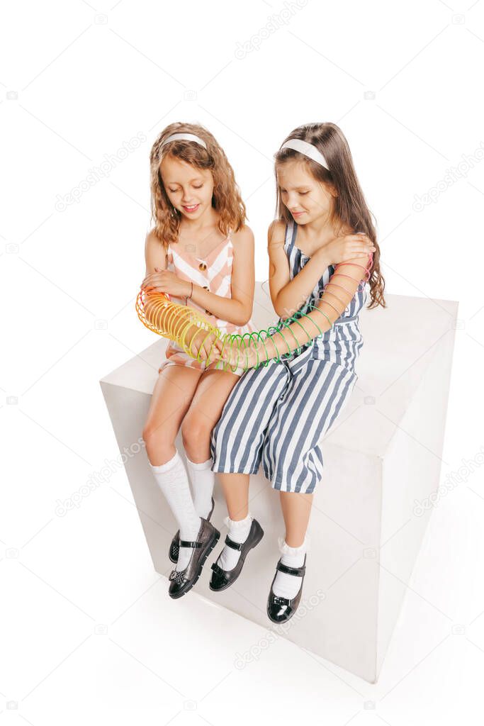 High angle view of two cheerful girls in retro style summer outfit isolated on white background. Concept of kids emotions, facial expression, beauty, childhood. Copy space for ad