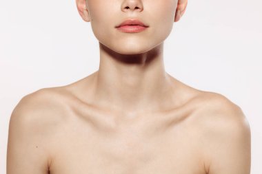 Kadın boynuna yakın, köprücük kemikleri beyaz stüdyo arka planında izole edilmiş. İyi korunmuş ciltli güzel bir genç kadın vücudu. Doğal güzellik, fitness, diyet, spa, estetik cerrahi ve estetik kozmetoloji
