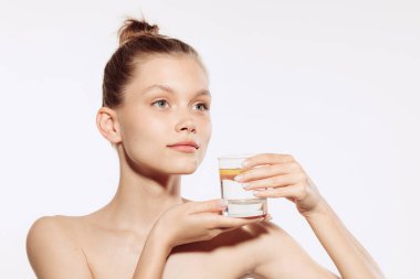 İyi korunmuş deri. Beyaz arka planda, makyajsız genç ve güzel bir kadın modelin yarım boy portresi. Güzellik, kaplıca, masaj, yüz gerdirme ve cilt bakımı