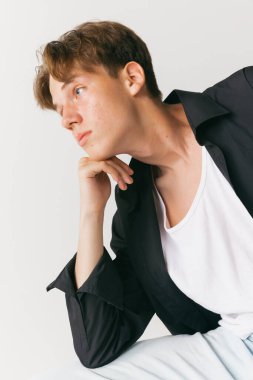 - Yakın çekim. Beyaz stüdyo arka planında izole edilmiş yakışıklı erkek portresi. Moda anlayışı, gençlik, duygular, yüz ifadesi, reklam. Moda erkek modelleri gündelik kıyafetlerle poz veriyor. Sakin, ciddi görünüyor.