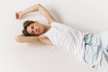 Duygular. Genç, yakışıklı bir adamın havadan görünüşü, beyaz arka planda izole edilmiş günlük kıyafetler giyen bir öğrenci. Sanat, güzellik, moda, gençlik kültürü, satış ve reklamlar